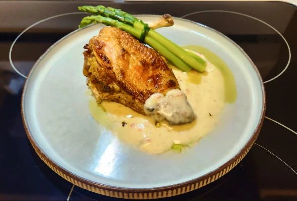 An appetizing meal of chicken on a creamy sauce, and asparagus on the side